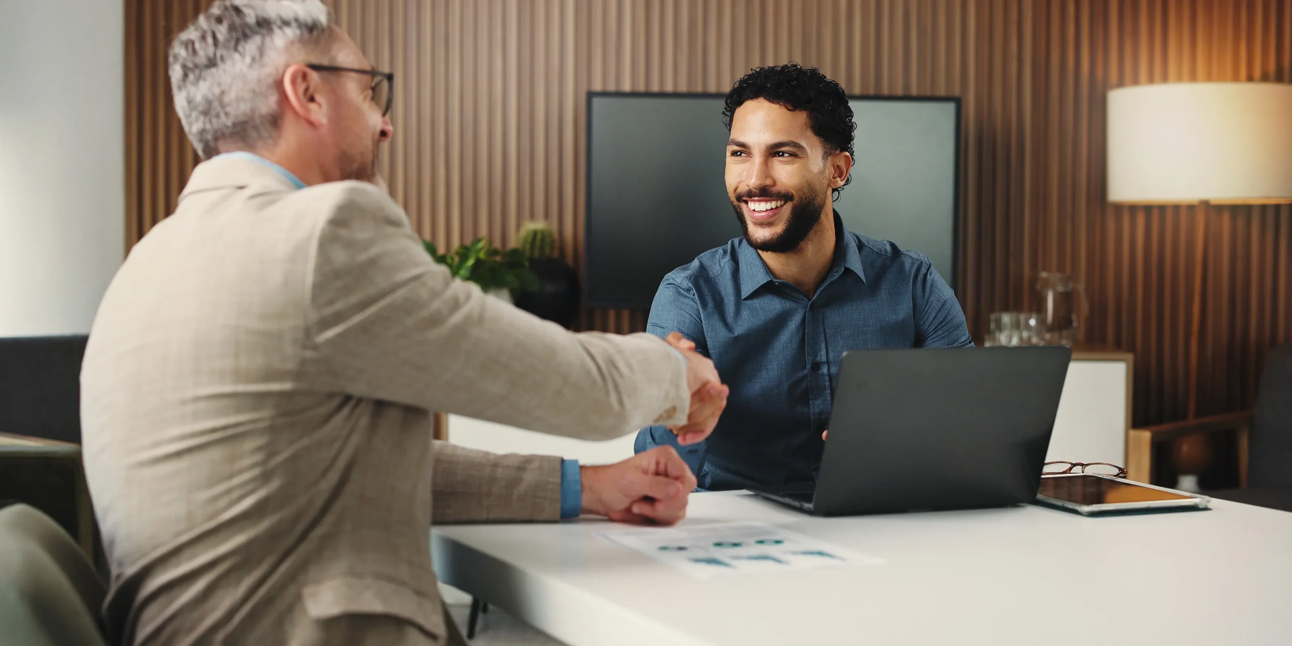 Zwei Männer geben sich nach einem Gespräch am Besprechungstisch die Hand